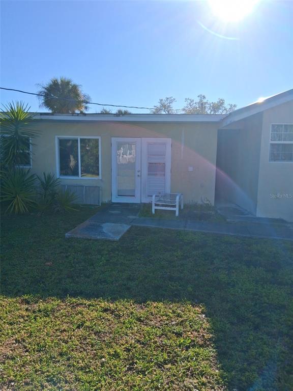 A view of a house exterior featuring a glass door, windows, and a small patio — 3311 ASH STREET, PUNTA GORDA, FL