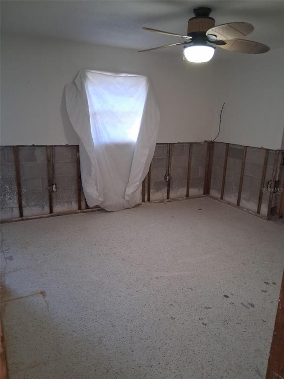 An unfinished room with exposed concrete block walls, a concrete floor, and a ceiling fan — 3311 ASH STREET, PUNTA GORDA, FL