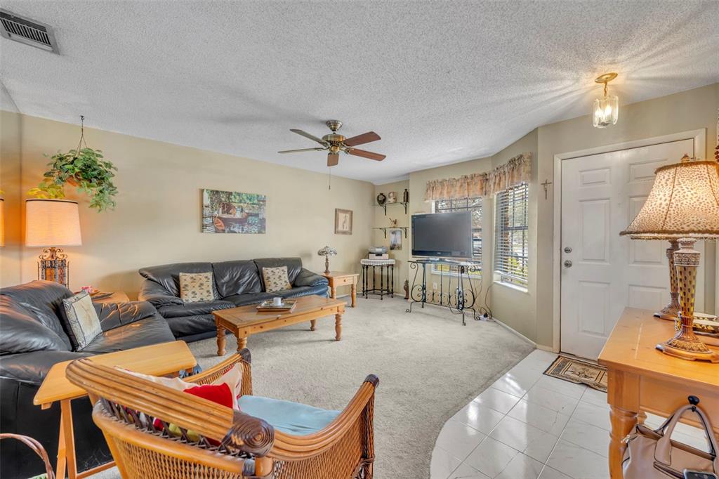 A living room features a leather sofa, a wicker chair, and a television on a stand — 838 COMMONWEALTH COURT, CASSELBERRY, FL