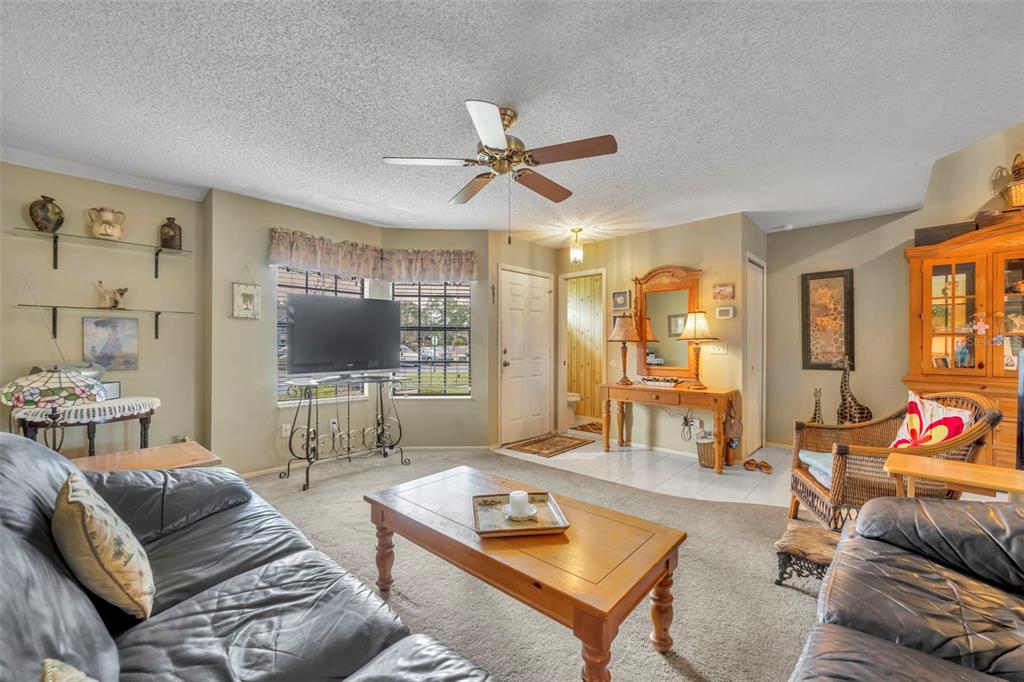 A living room features a ceiling fan, leather sofas, a coffee table, and a television — 838 COMMONWEALTH COURT, CASSELBERRY, FL