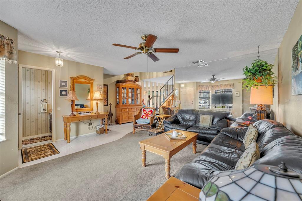 A living room features a carpeted floor, leather sofas, a wooden coffee table, and stairs — 838 COMMONWEALTH COURT, CASSELBERRY, FL
