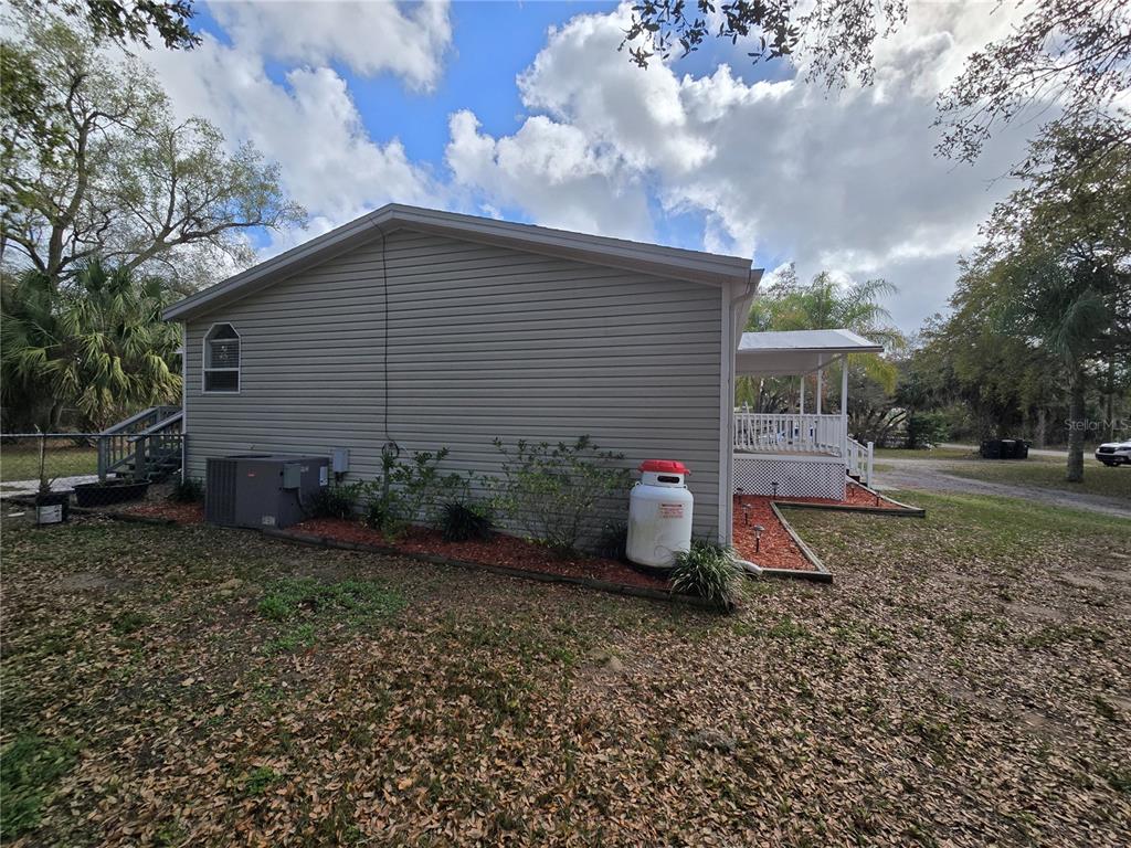 The exterior of a house features light gray siding, a propane tank, and a porch — 5304 FAIRMONT ROAD, LAKE WALES, FL