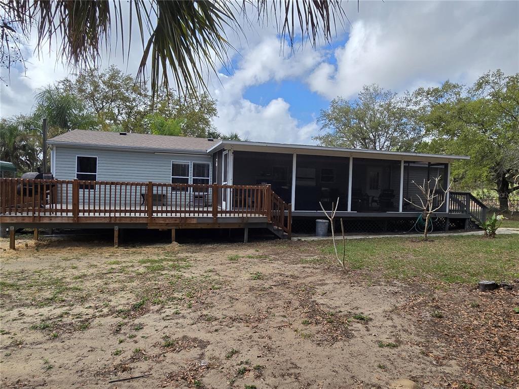 A house exterior features a wooden deck and a large screened-in porch in the backyard — 5304 FAIRMONT ROAD, LAKE WALES, FL