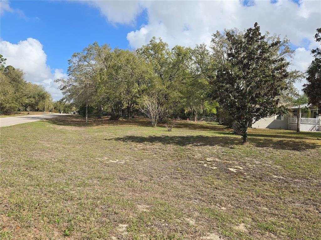 A grassy, partially wooded vacant lot sits next to a house with a porch — 5304 FAIRMONT ROAD, LAKE WALES, FL
