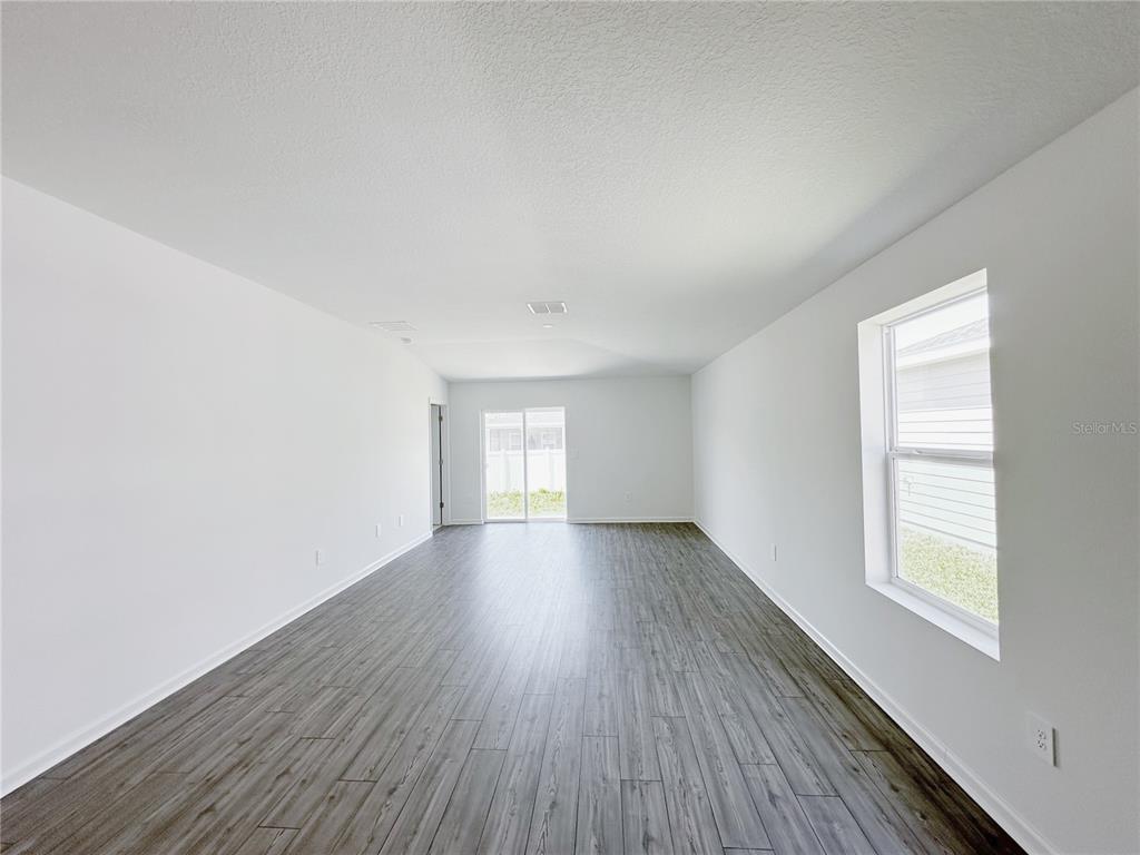 A hallway with light gray walls, wood-look flooring, and white doors leading to an entrance — 8414 SW 41 CIRCLE, OCALA, FL