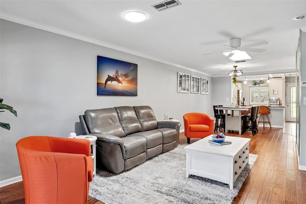 A living room features a gray leather sofa, two orange armchairs, and a white coffee table — 3259 HILARY CIRCLE UNIT 1C, PALM HARBOR, FL