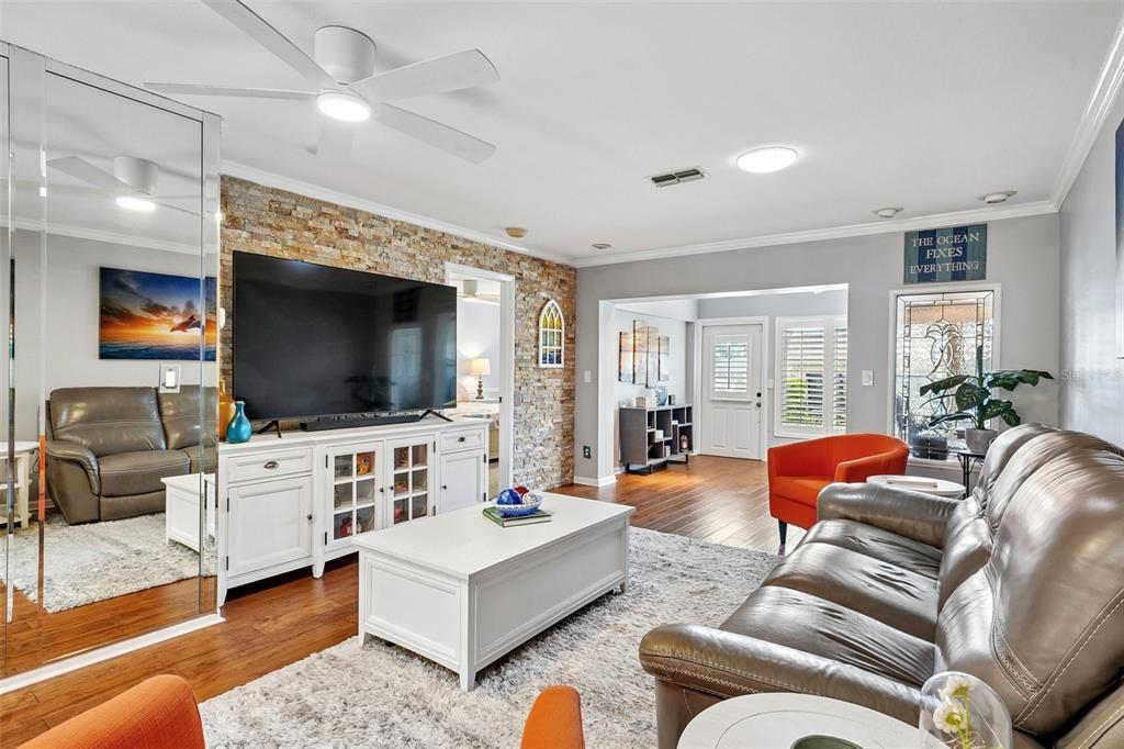 A home office features wood flooring, plantation shutters, a ceiling fan, and a large wall clock — 3259 HILARY CIRCLE UNIT 1C, PALM HARBOR, FL