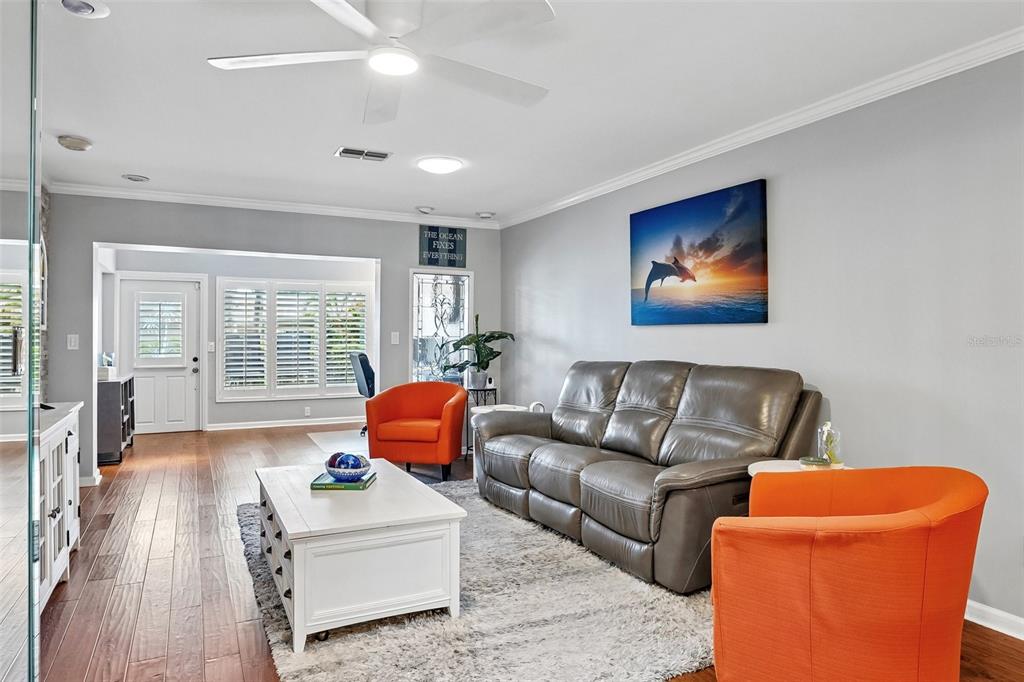 A home office area with a desk and computer monitors sits adjacent to a living room — 3259 HILARY CIRCLE UNIT 1C, PALM HARBOR, FL
