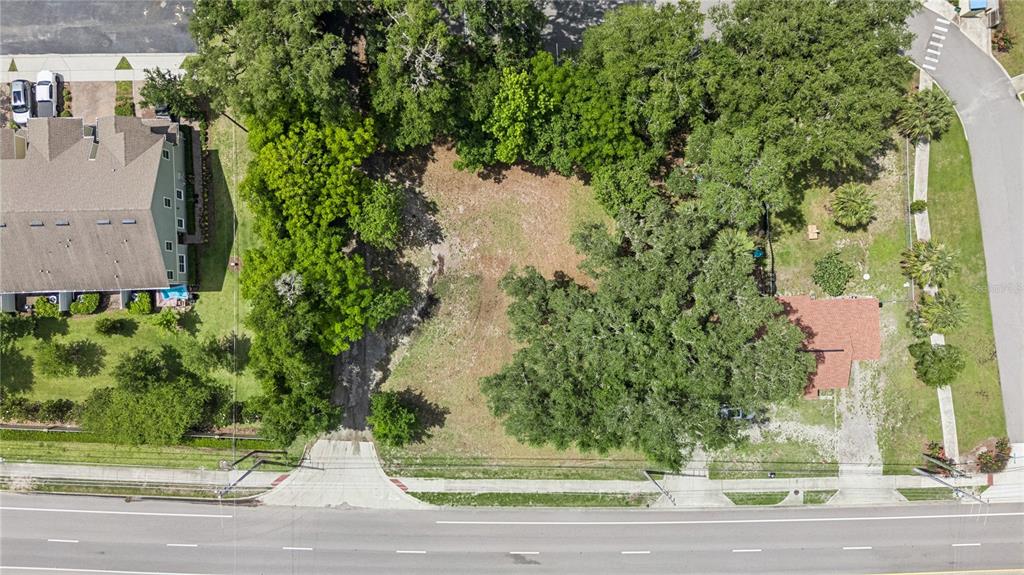 An aerial view shows a vacant, tree-lined lot situated between a residential building and a house — 0000 N RONALD REAGAN BLVD, SANFORD, FL