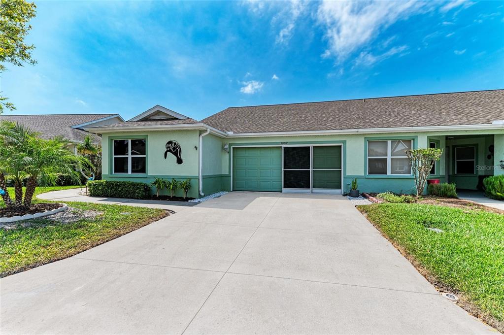 A light green single-story house with a concrete driveway and a two-car garage — 3009 LIVE OAK LANE, PALMETTO, FL