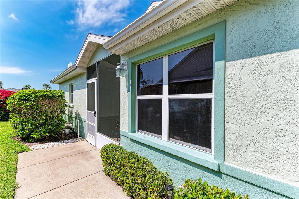 A light green stucco house exterior features a screened-in porch and a large window — 3009 LIVE OAK LANE, PALMETTO, FL