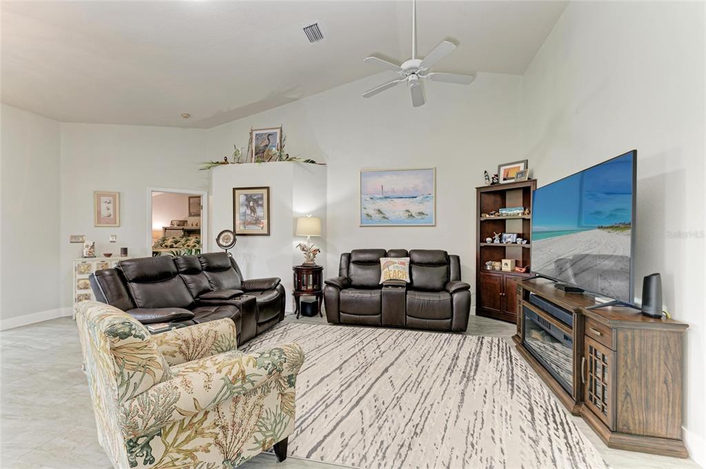 A living room features a vaulted ceiling, tiled floors, leather furniture, and a large television — 3009 LIVE OAK LANE, PALMETTO, FL