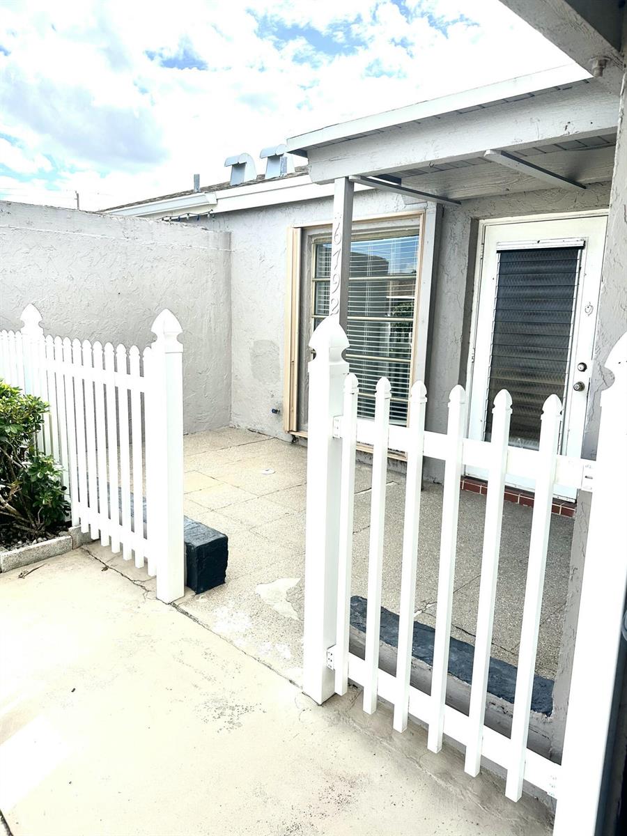 A white picket fence encloses a small concrete patio area in front of a building — 6792 Moonlit Drive, Delray Beach FL 33446, DELRAY BEACH, FL