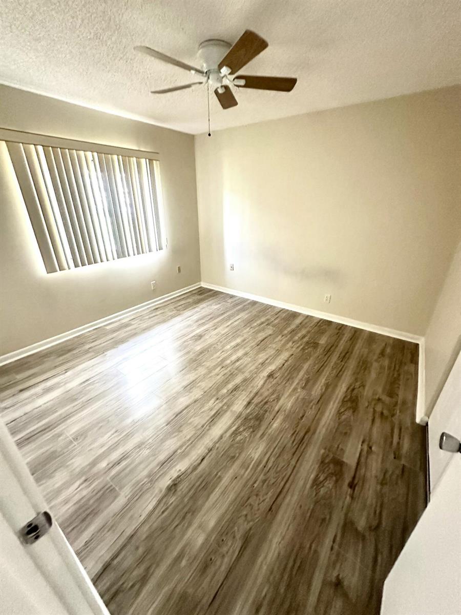 An empty bedroom features light-colored walls, a ceiling fan, and wood-look laminate flooring — 6792 Moonlit Drive, Delray Beach FL 33446, DELRAY BEACH, FL
