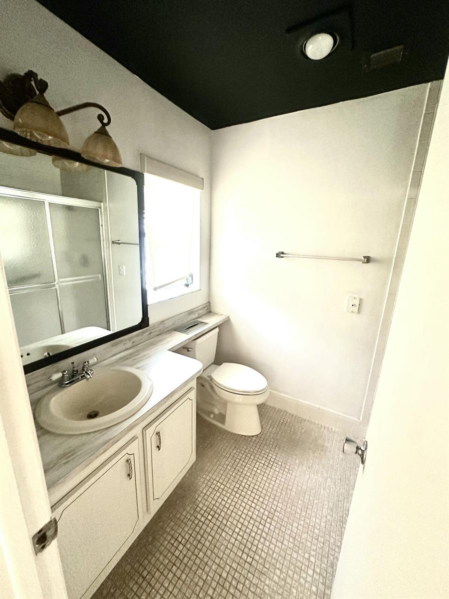 A bathroom features a vanity with a marble-look countertop, a toilet, and a black ceiling — 6792 Moonlit Drive, Delray Beach FL 33446, DELRAY BEACH, FL