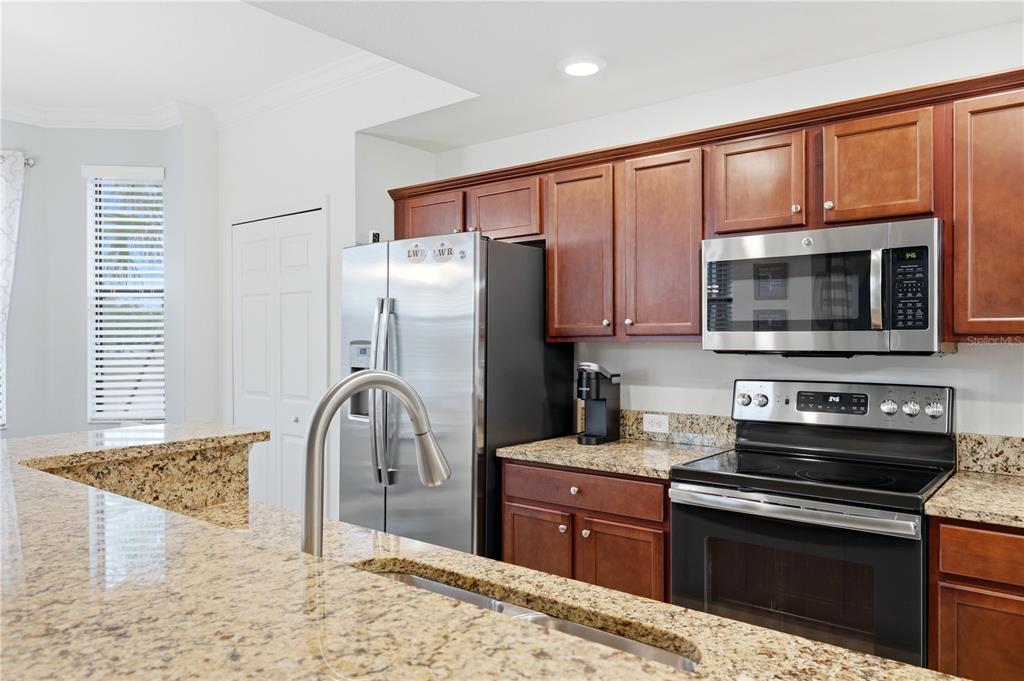 A kitchen features dark wood cabinets, granite countertops, and stainless steel appliances — 16804 VARDON TERRACE UNIT 103, BRADENTON, FL