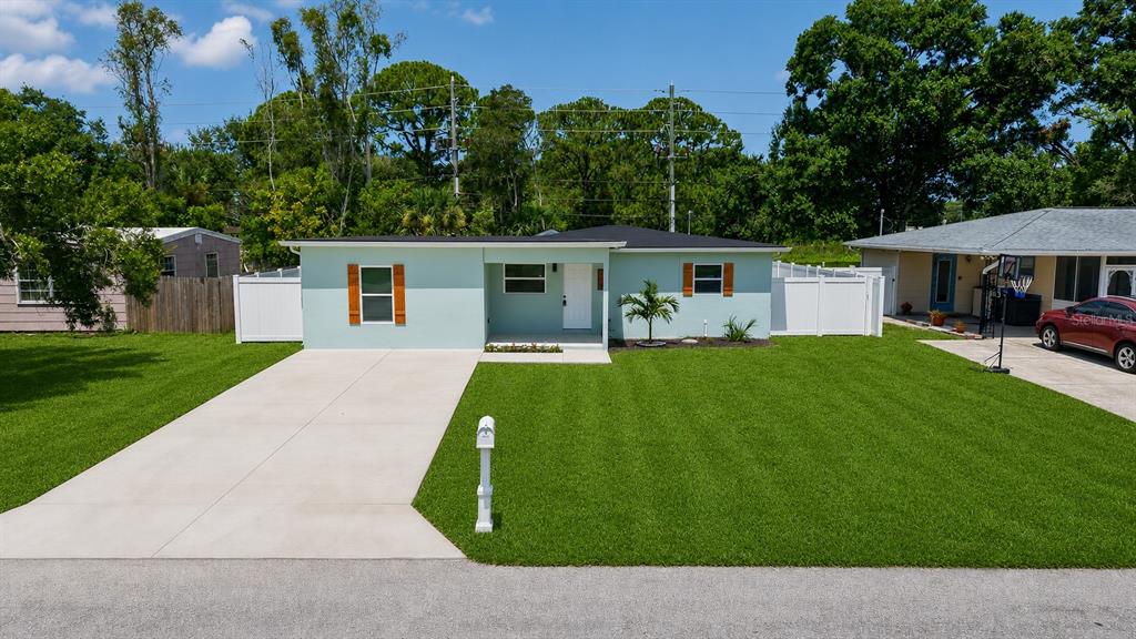 A light green single-story house with a concrete driveway and a white vinyl fence — 106 MELODY LANE, LARGO, FL