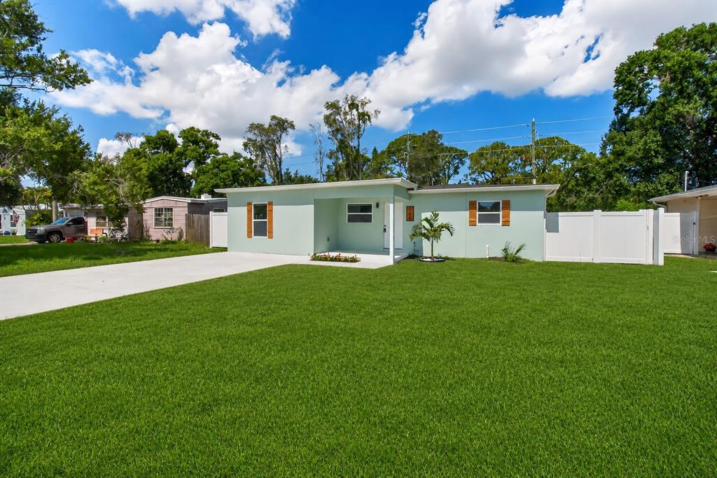 A light green single-story house with a concrete driveway and a white vinyl fence — 106 MELODY LANE, LARGO, FL
