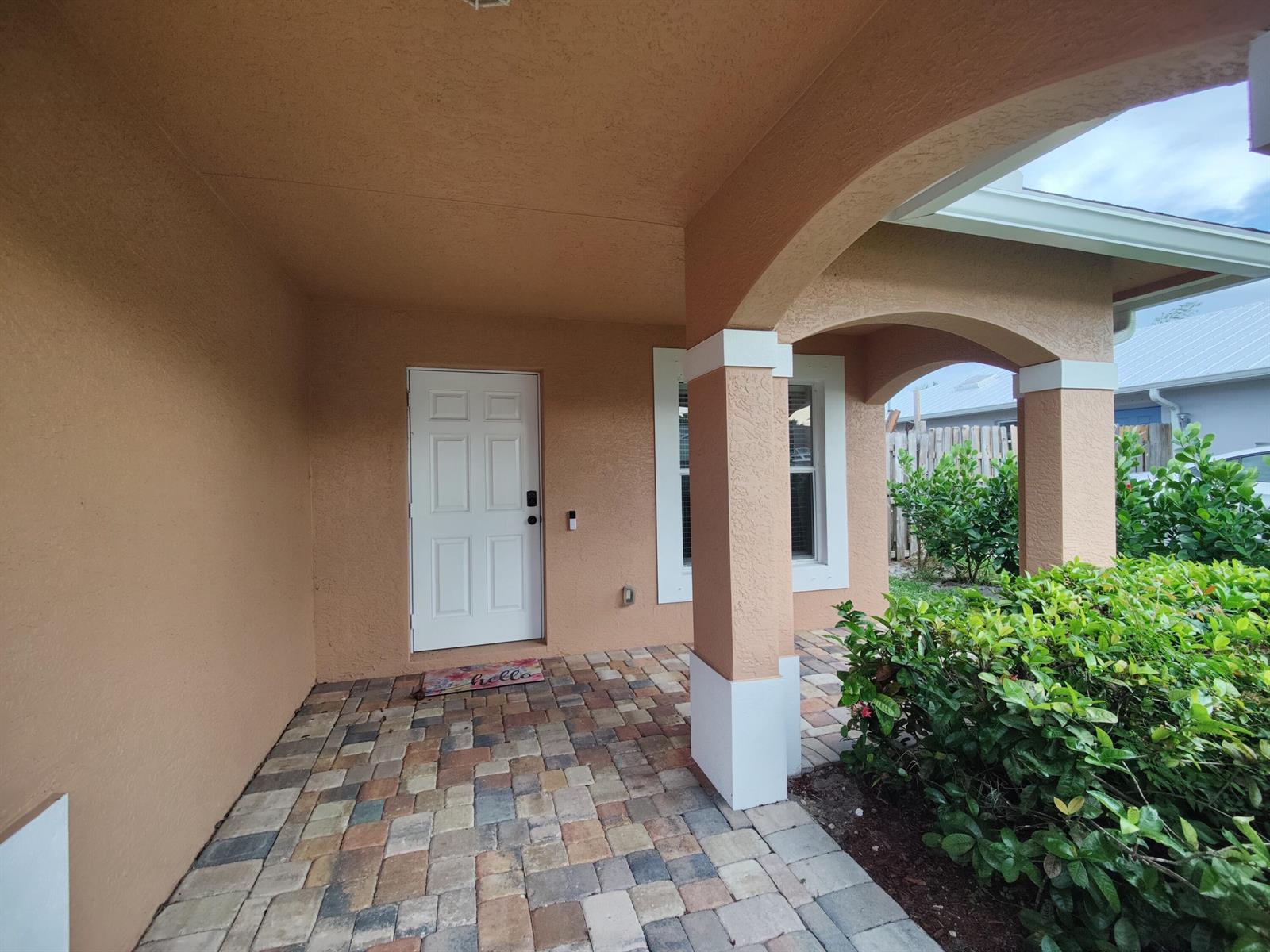 A covered entryway features a white door, paver flooring, and a stucco pillar — 5795 SE Mitzi Lane, Stuart FL 34997, STUART, FL