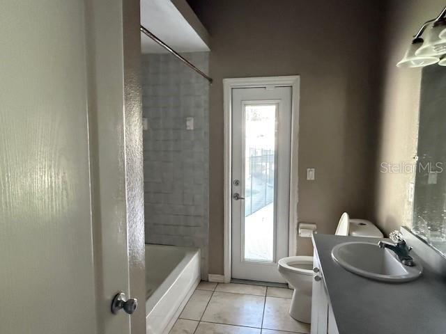 A bathroom features a shower-tub combo, a toilet, a vanity sink, and a glass-paneled door — 302 STERLING DRIVE, WINTER HAVEN, FL