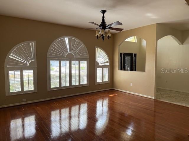 A living room with hardwood floors, a ceiling fan, and arched windows with shutters — 302 STERLING DRIVE, WINTER HAVEN, FL