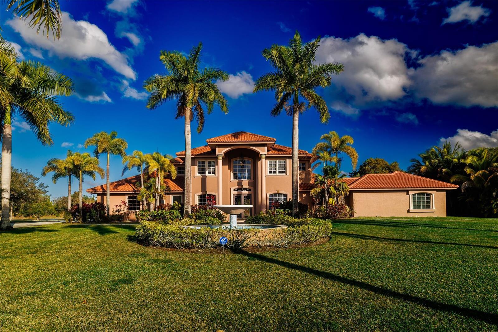 A two-story stucco house with a tile roof, palm trees, and a front yard fountain — 5660 Lago Del Sol Drive, Lake Worth FL 33449, LAKE WORTH, FL