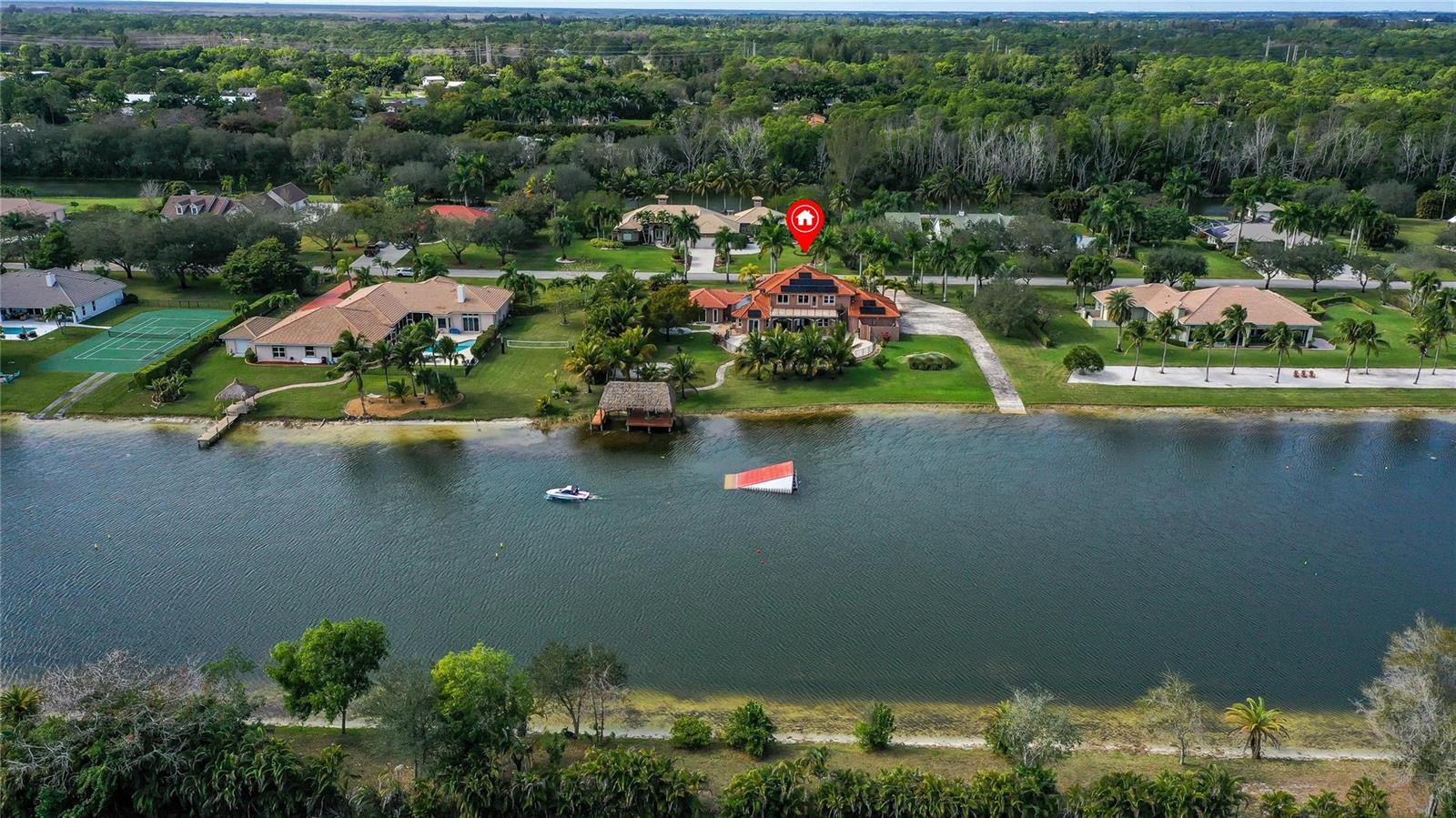 An aerial view of a waterfront house with a pool, tennis court, and boat dock — 5660 Lago Del Sol Drive, Lake Worth FL 33449, LAKE WORTH, FL