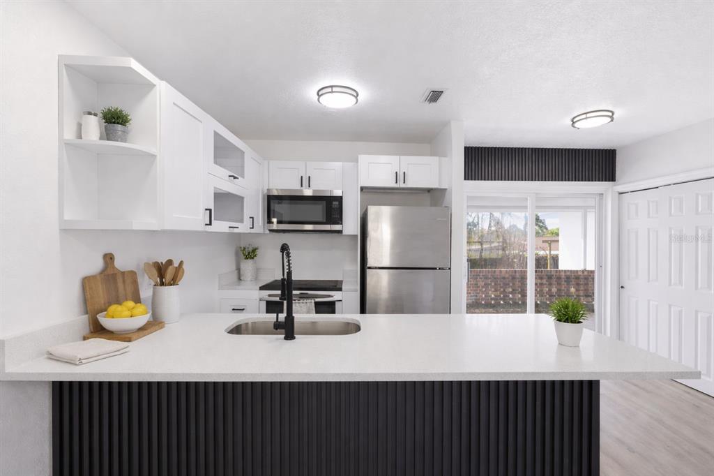 A modern kitchen features white cabinets, stainless steel appliances, and a dark slatted kitchen island — 113 EASTWAY DR, LAKELAND, FL