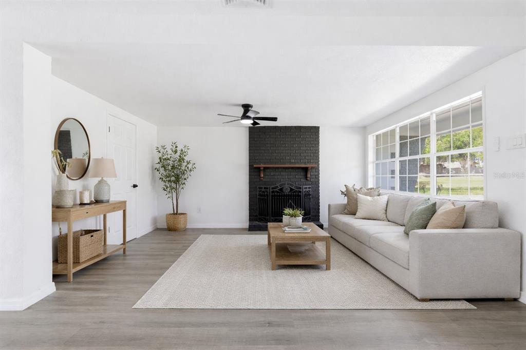 A living room features a black brick fireplace, light gray flooring, and a beige sofa — 113 EASTWAY DR, LAKELAND, FL