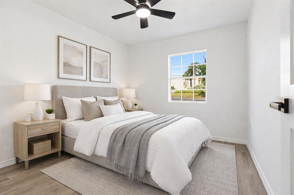A bedroom features a bed with white bedding, a grey throw, and a ceiling fan — 113 EASTWAY DR, LAKELAND, FL