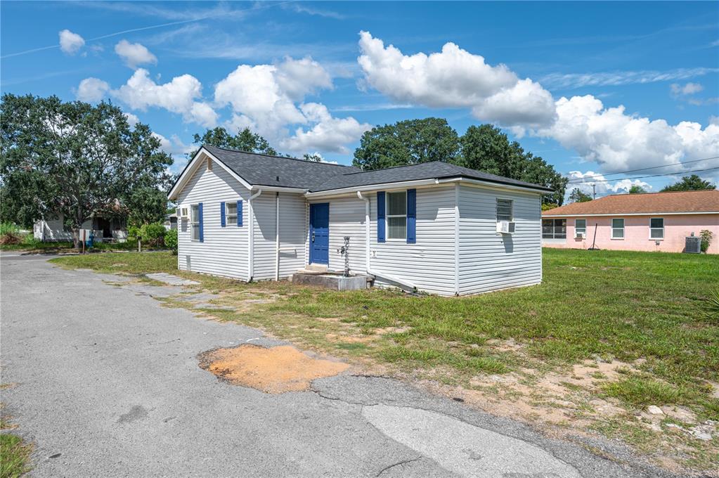 A single-story white house with a blue door sits on a grassy lot — 520 W JACKSON AVENUE, LAKE WALES, FL