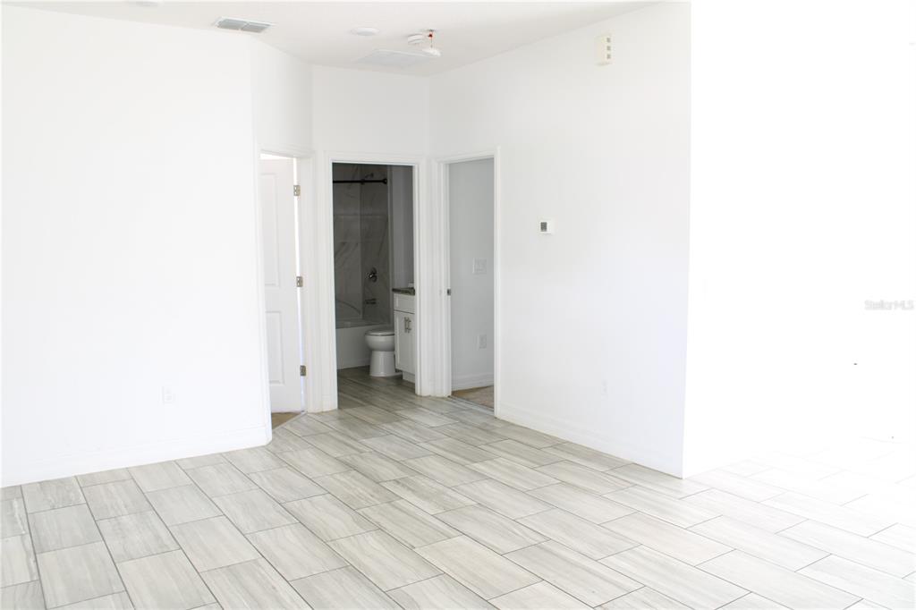 A room with light-colored tile flooring and three doorways leading to a bathroom and other areas — 104 HERRING WAY, KISSIMMEE, FL