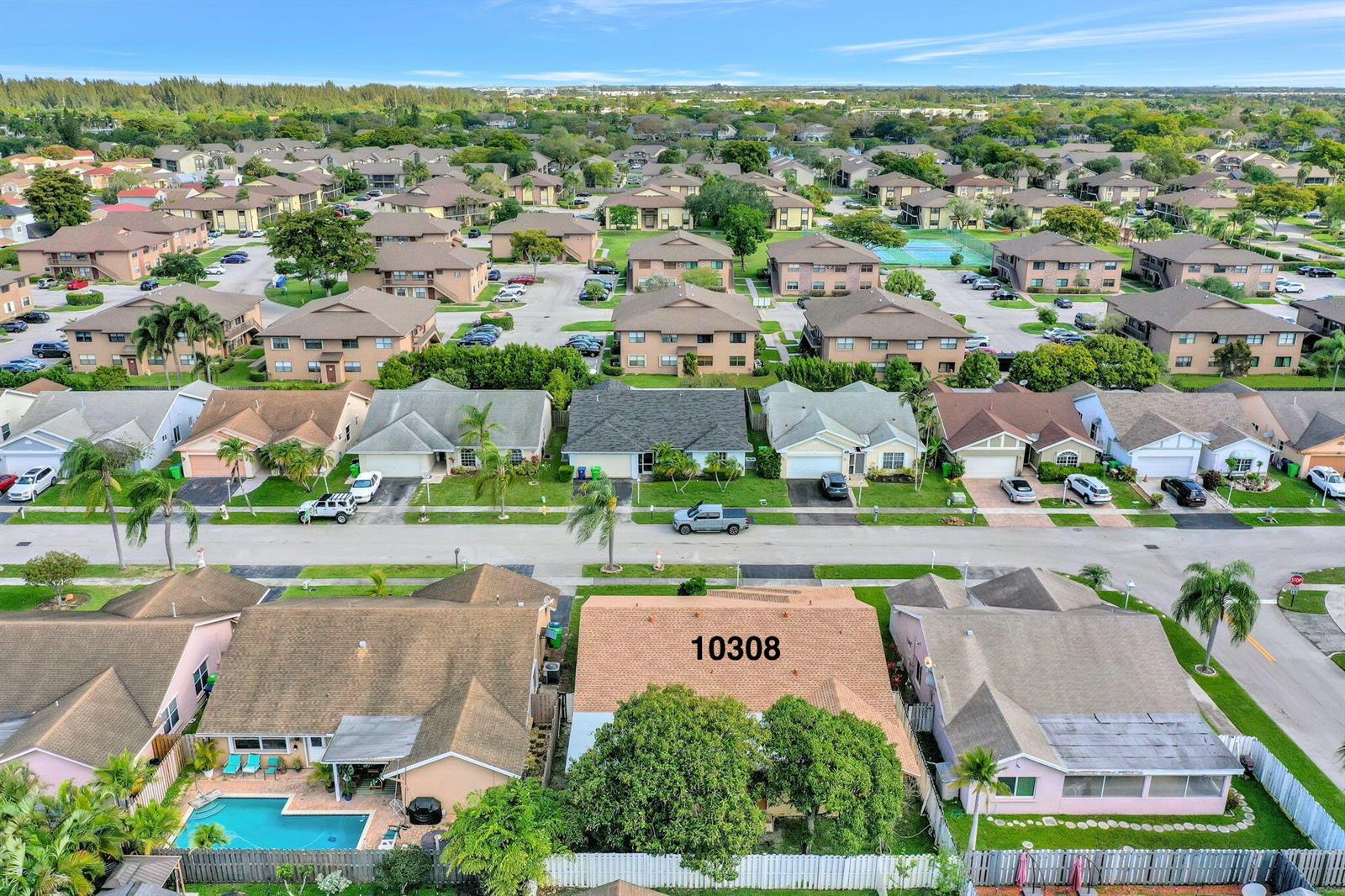 An aerial view shows a residential neighborhood with single-family homes and multi-story apartment buildings — 10308 Welleby Isles Lane, Sunrise FL 33351, SUNRISE, FL