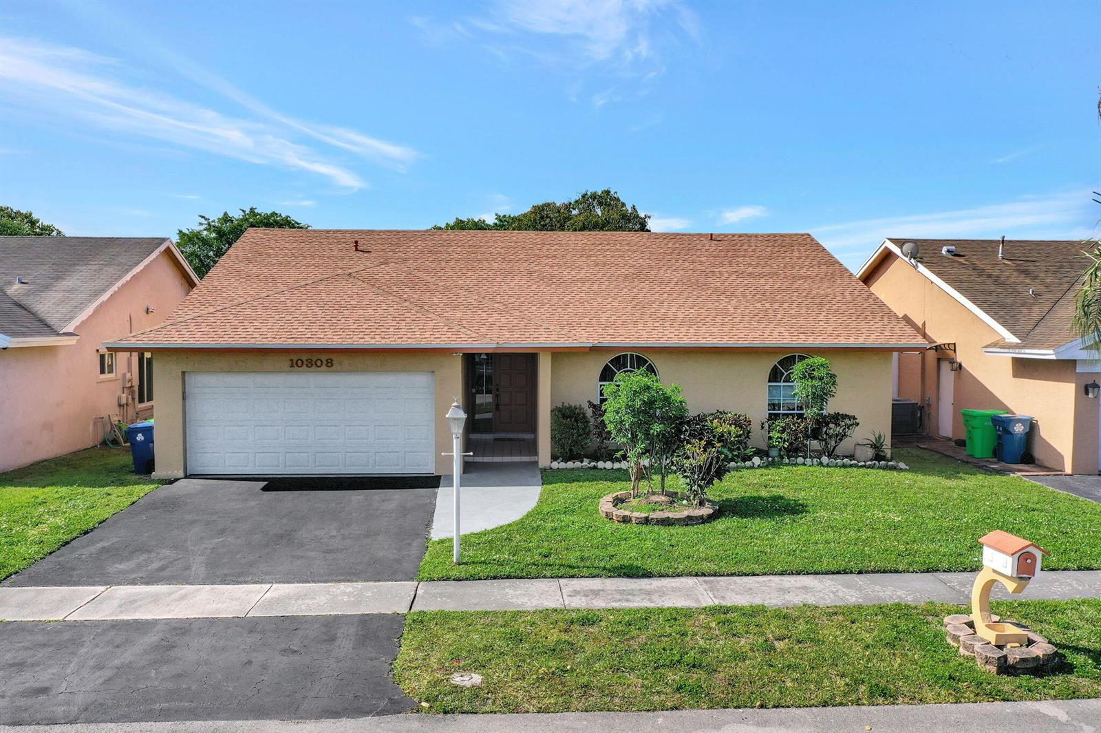 A single-story house with a tan stucco exterior, brown shingle roof, and a two-car garage — 10308 Welleby Isles Lane, Sunrise FL 33351, SUNRISE, FL