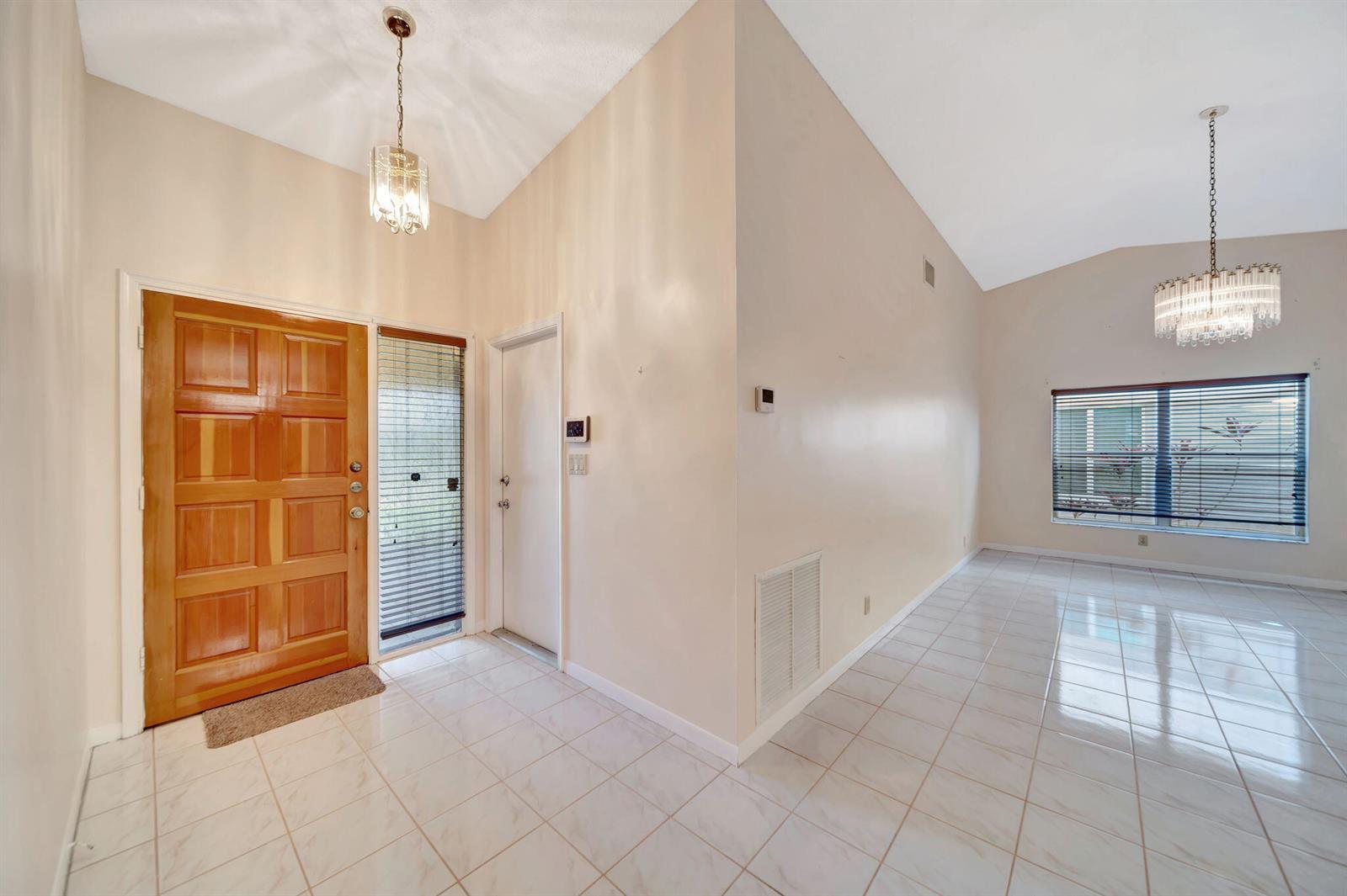An entryway with a wooden door, tiled floors, and two hanging light fixtures — 10308 Welleby Isles Lane, Sunrise FL 33351, SUNRISE, FL