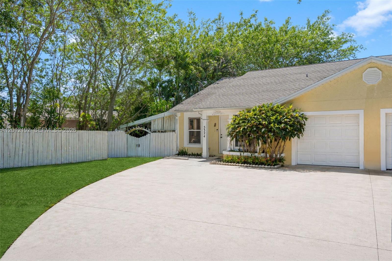 A yellow single-story house features a concrete driveway, a white fence, and a garage — 5324 GRAY FOX CT, West Palm Beach FL 33415, WEST PALM BEACH, FL