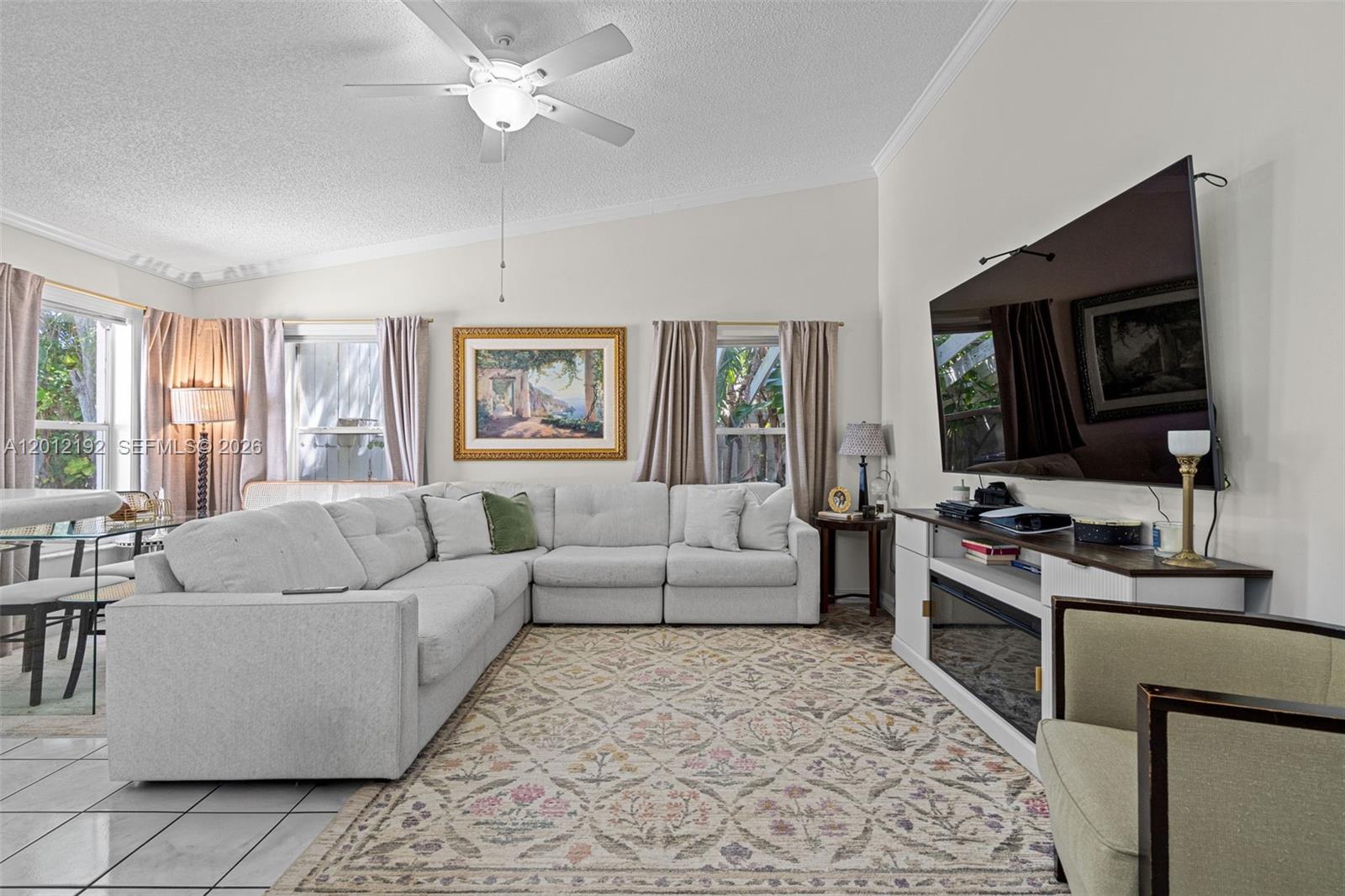 A living room features a large sectional sofa, a patterned rug, and a wall-mounted television — 5324 GRAY FOX CT, West Palm Beach FL 33415, WEST PALM BEACH, FL