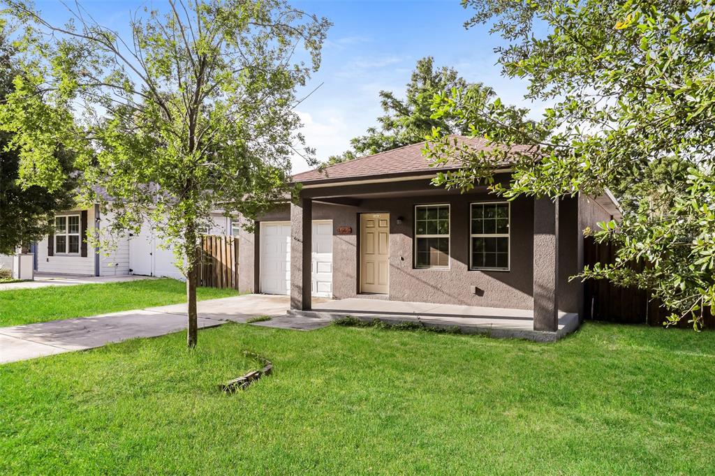A single-story house with a dark stucco exterior, a covered front porch, and a concrete driveway — 1505 E CARACAS STREET, TAMPA, FL