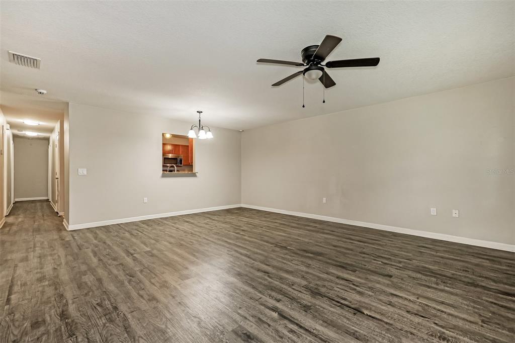 A living room with wood-look flooring, a ceiling fan, and a pass-through to the kitchen — 1505 E CARACAS STREET, TAMPA, FL
