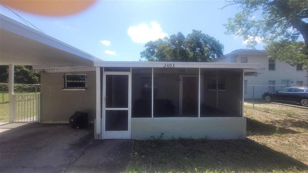 A house exterior featuring a screened-in front porch, a carport, and a concrete driveway — 3403 TEMPLE STREET, TAMPA, FL