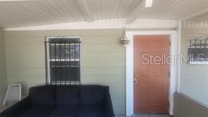A covered porch features a dark sofa, a window with security bars, and a brown door — 3403 TEMPLE STREET, TAMPA, FL