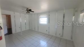 A room with white tiled floors, white walls with vertical mirror strips, and a ceiling fan — 3403 TEMPLE STREET, TAMPA, FL