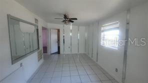 A room with white tiled floors, mirrored wall panels, and a ceiling fan — 3403 TEMPLE STREET, TAMPA, FL
