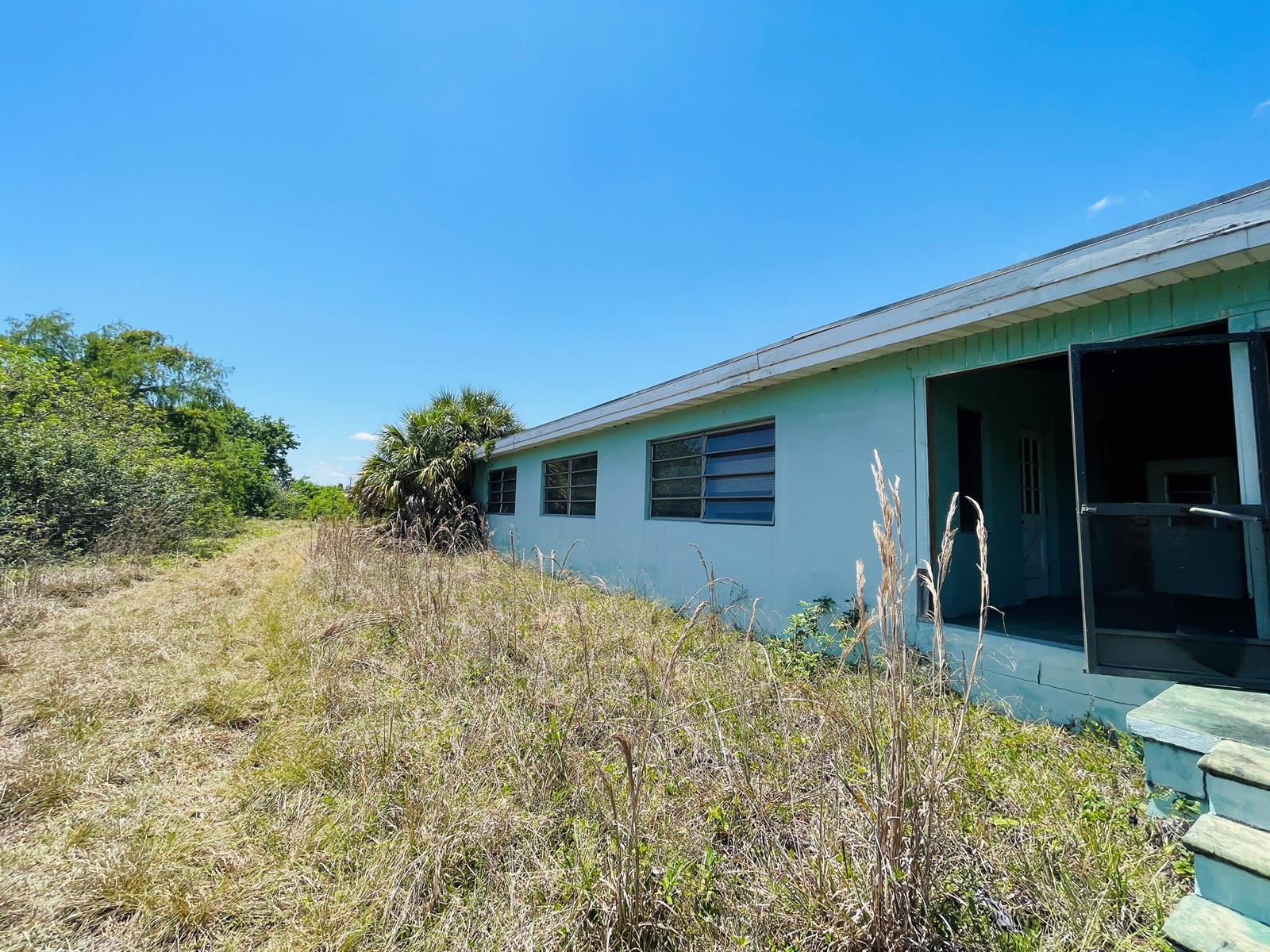 The exterior of a light green house with jalousie windows and a screened-in porch — 265 State Rd 78, Moore Haven FL 33471, MOORE HAVEN, FL