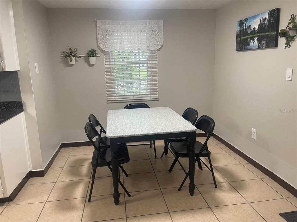 A dining area features a speckled table, four black chairs, and tile flooring — 8415 N GOMEZ AVENUE, TAMPA, FL