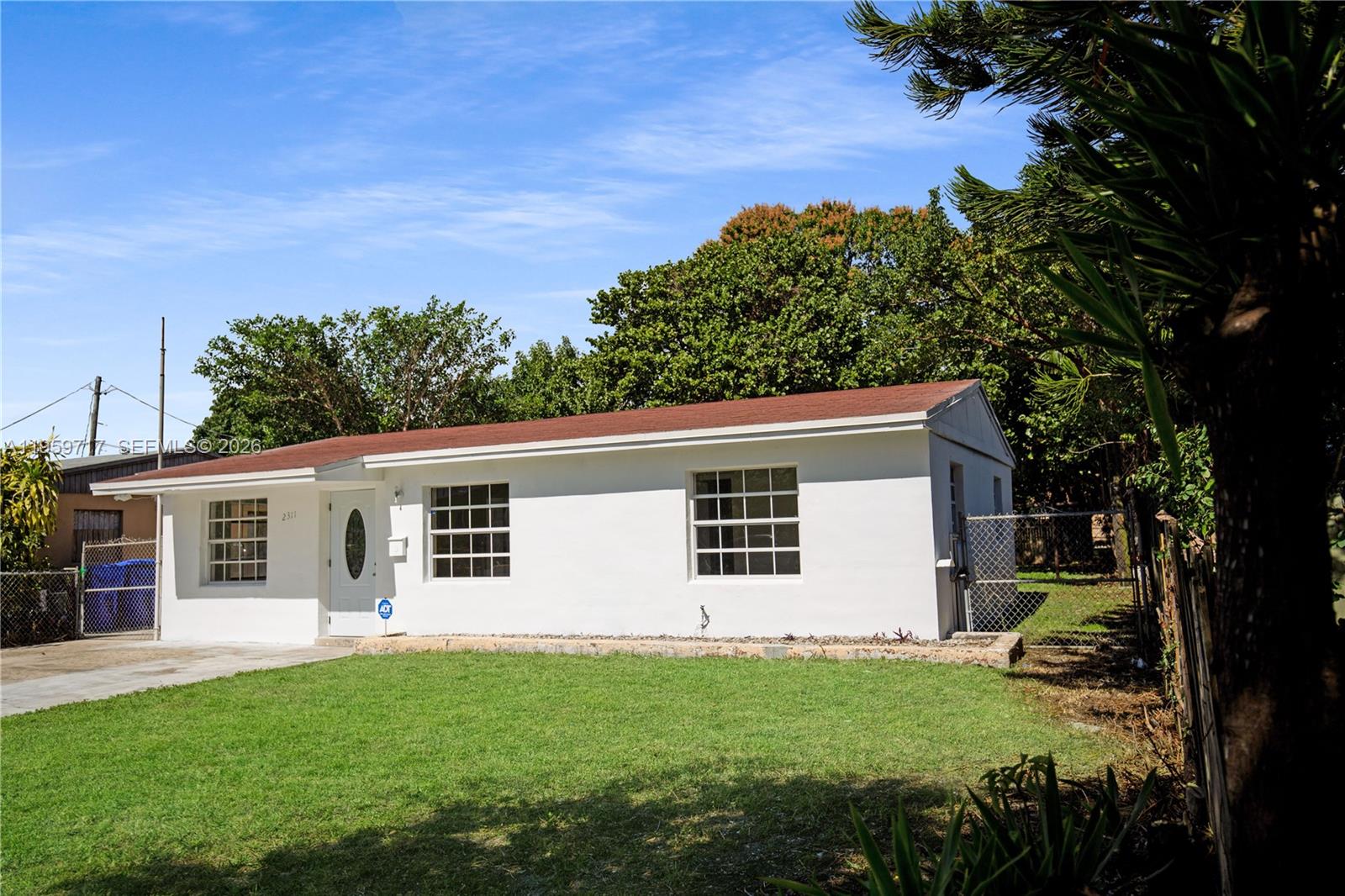 A kitchen features white cabinets, stainless steel appliances, a granite island, and wood-look flooring — 2311 Fletcher St, Hollywood FL 33020, HOLLYWOOD, FL