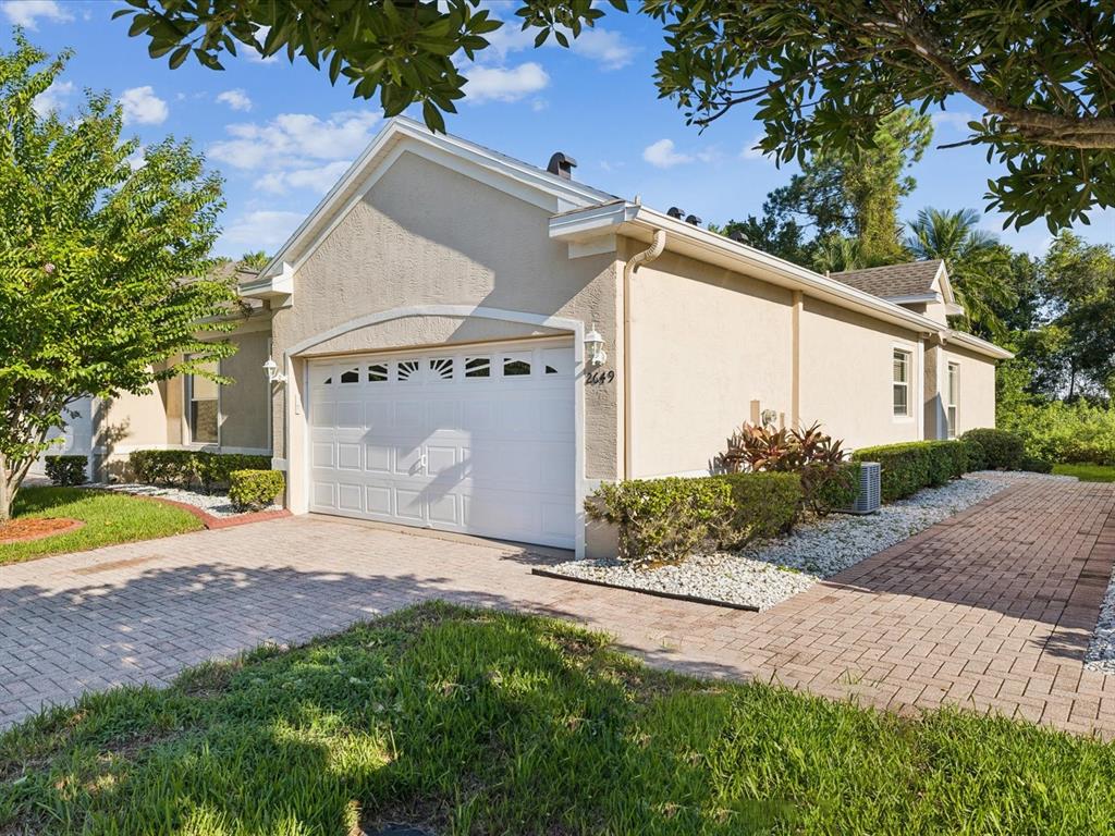 A beige single-story house with a white garage door and a brick paver driveway — 2649 TOTTENHAM DRIVE, NEW PORT RICHEY, FL