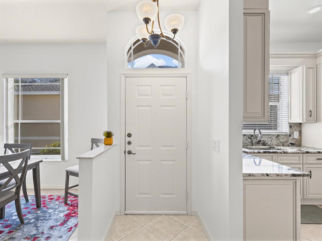 An entryway with a white front door, arched transom window, and adjacent kitchen and dining area — 2649 TOTTENHAM DRIVE, NEW PORT RICHEY, FL