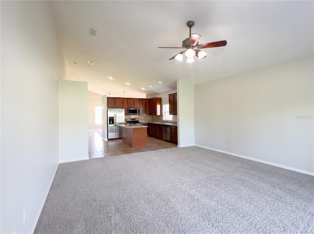 A carpeted living room opens into a kitchen with dark wood cabinets and stainless appliances — 457 MARATHON LANE, SANFORD, FL