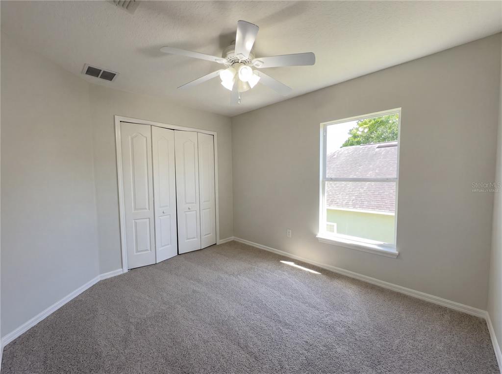A bedroom features light gray walls, beige carpeting, a ceiling fan, and a white closet — 457 MARATHON LANE, SANFORD, FL